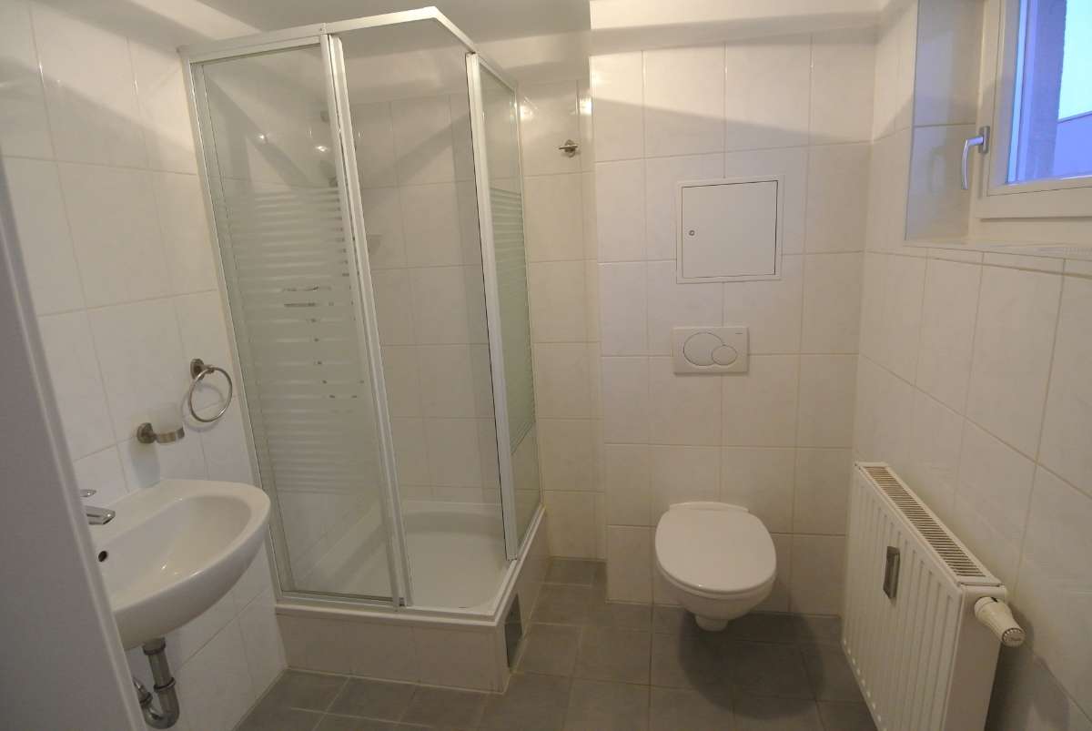 Kleines Badezimmer mit Dusche, Waschbecken, WC und kleinem Fenster