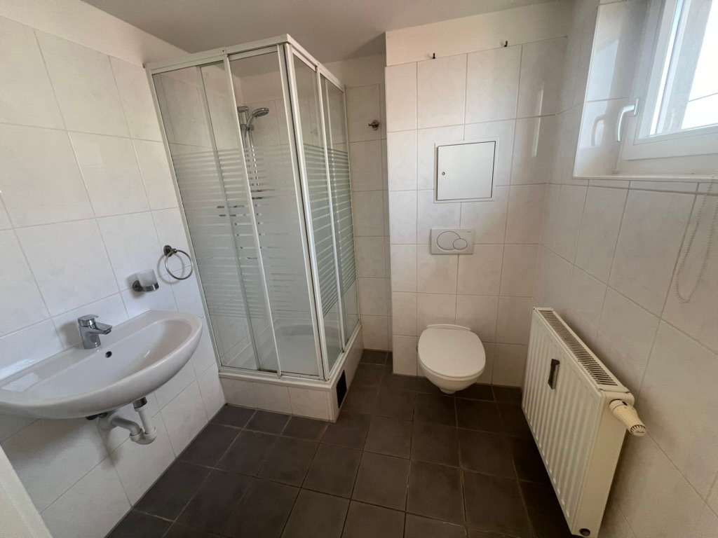 Badezimmer mit Eckdusche, WC, Waschbecken und Fenster