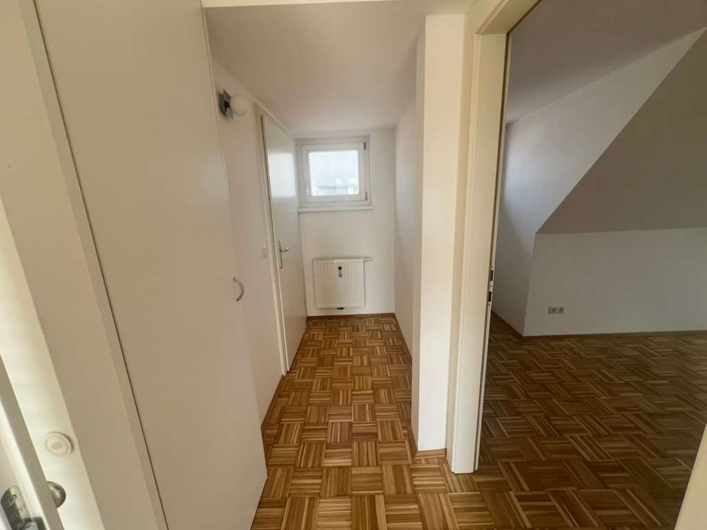 Kleiner Flur mit Parkettboden, weiß gestrichenen Wänden und Tür zu weiterem Raum