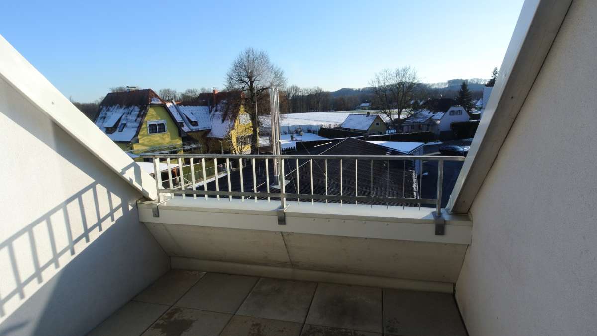 Schmaler Balkon mit Fliesenboden, Metallgeländer und Ausblick auf verschneite Umgebung