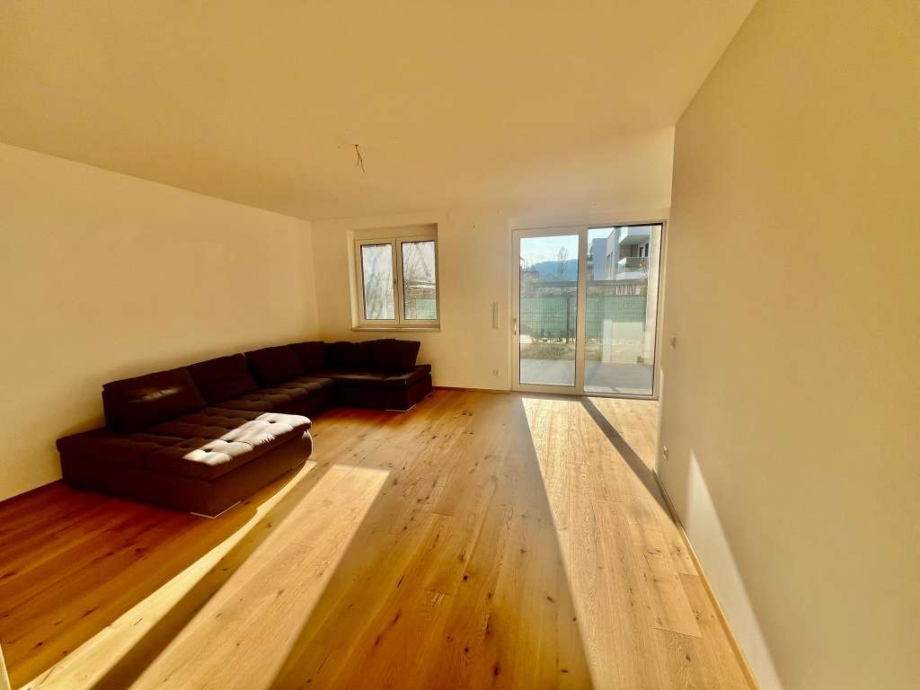 Wohnzimmer mit großer Eckcouch, Holzboden und Zugang zur Terrasse