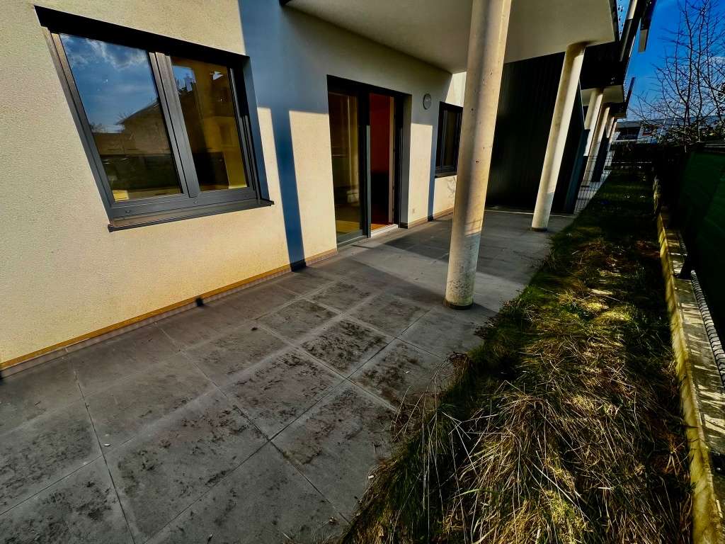 Terrasse mit Fliesenbelag vor modernem Gebäude mit großen Fenstern