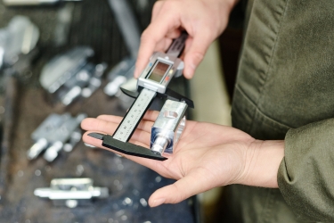 Person measuring metal parts with a caliber