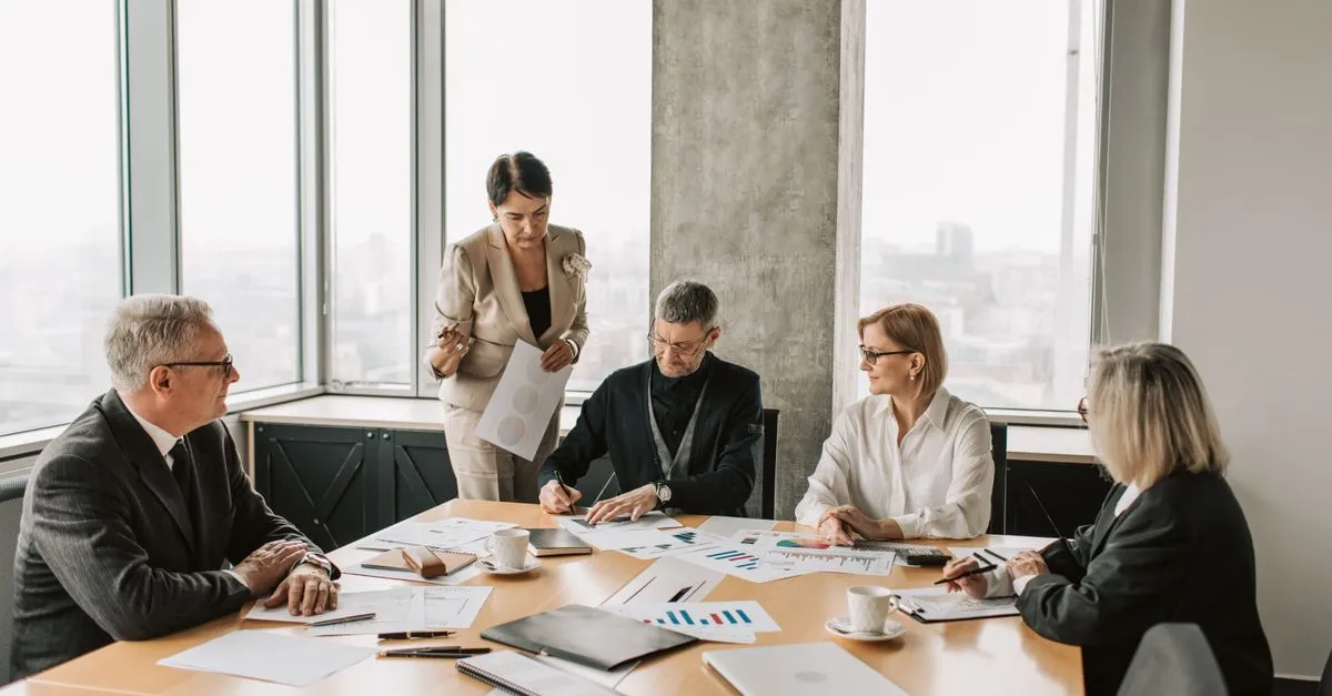 A business team reviewing plans and printed research around a table