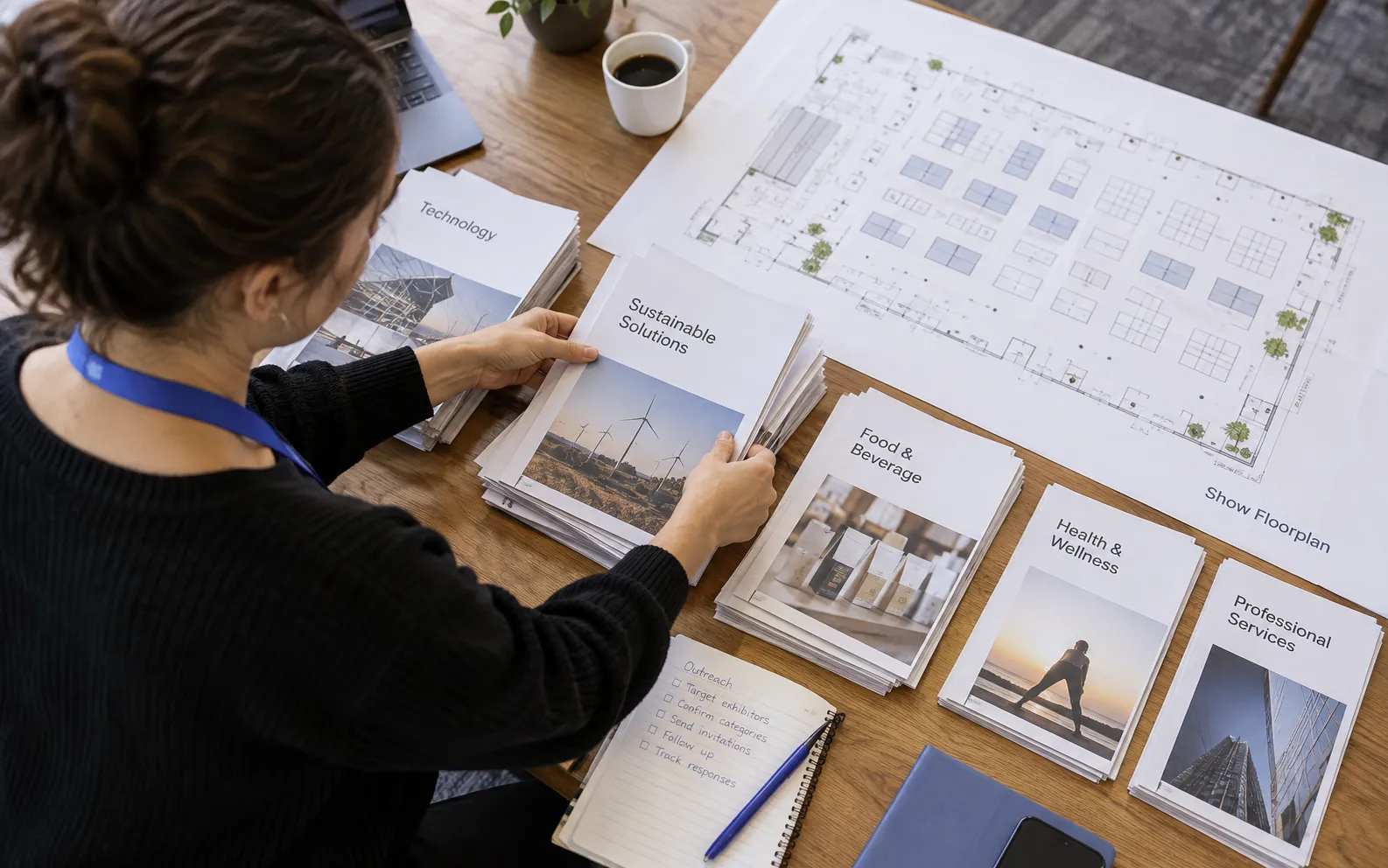Generated scenario: An event acquisition planner sorts prospective exhibitor and sponsor company folders into focused category groups beside a physical show floorplan