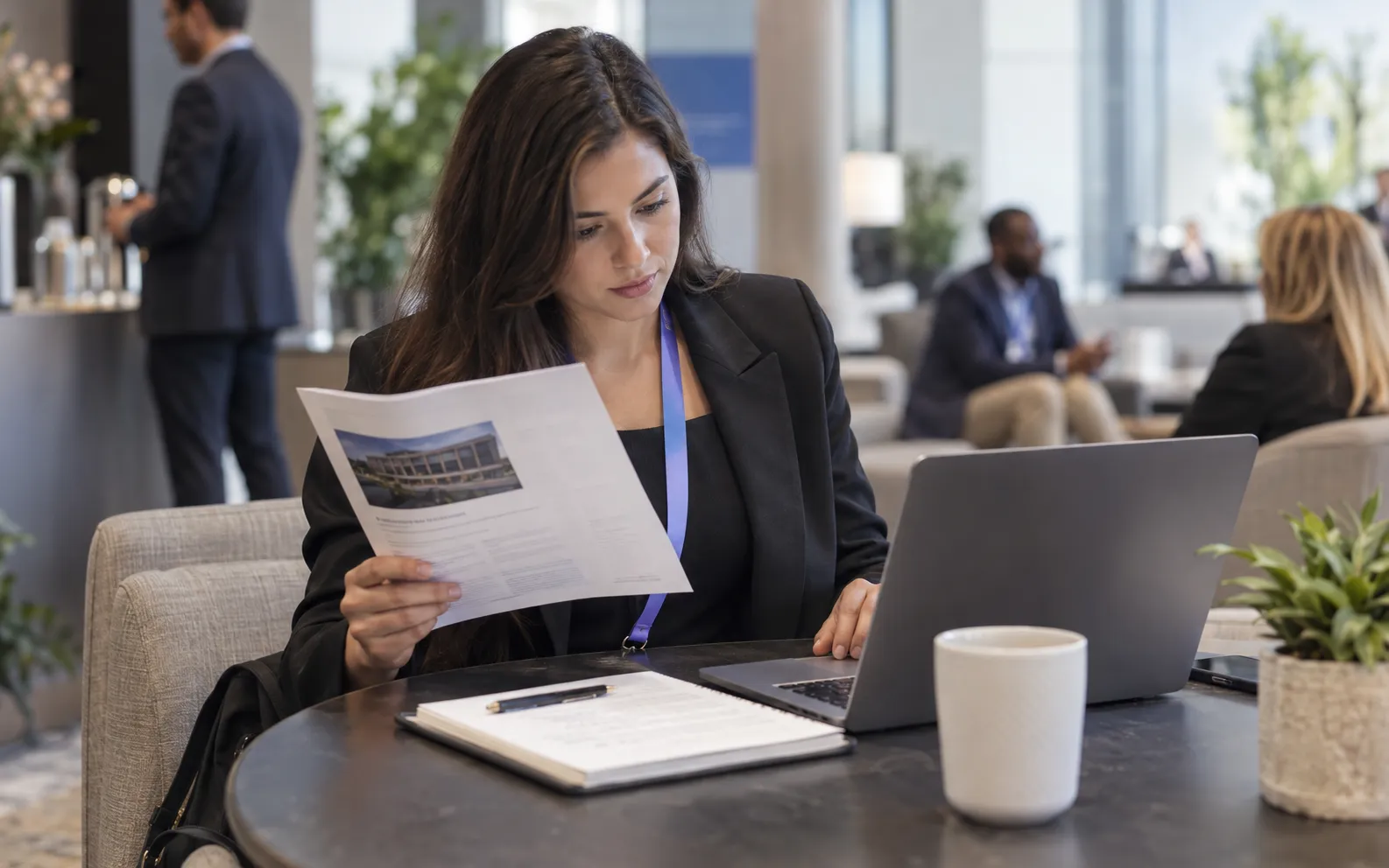 Generated scenario: A sales researcher studies a printed company overview and relevant role notes at a laptop in a venue lounge