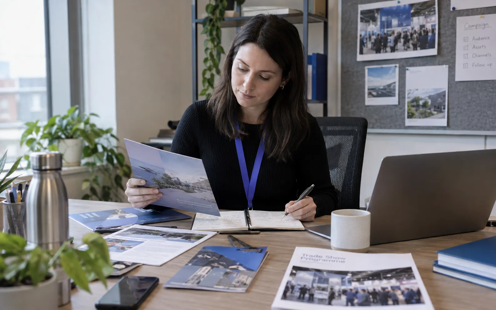 Generated scenario: A demand generation planner reviews an offer brief with sector-specific product brochures and an upcoming trade-show programme in a modest office