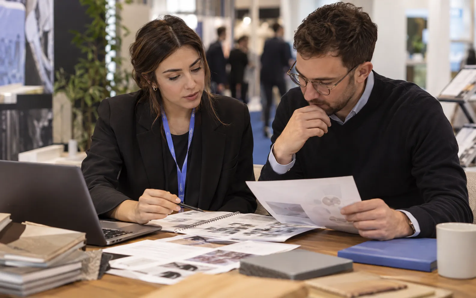 Generated scenario: An event campaign planner compares target company profiles with a product audience brief at a table with unbranded stand material samples