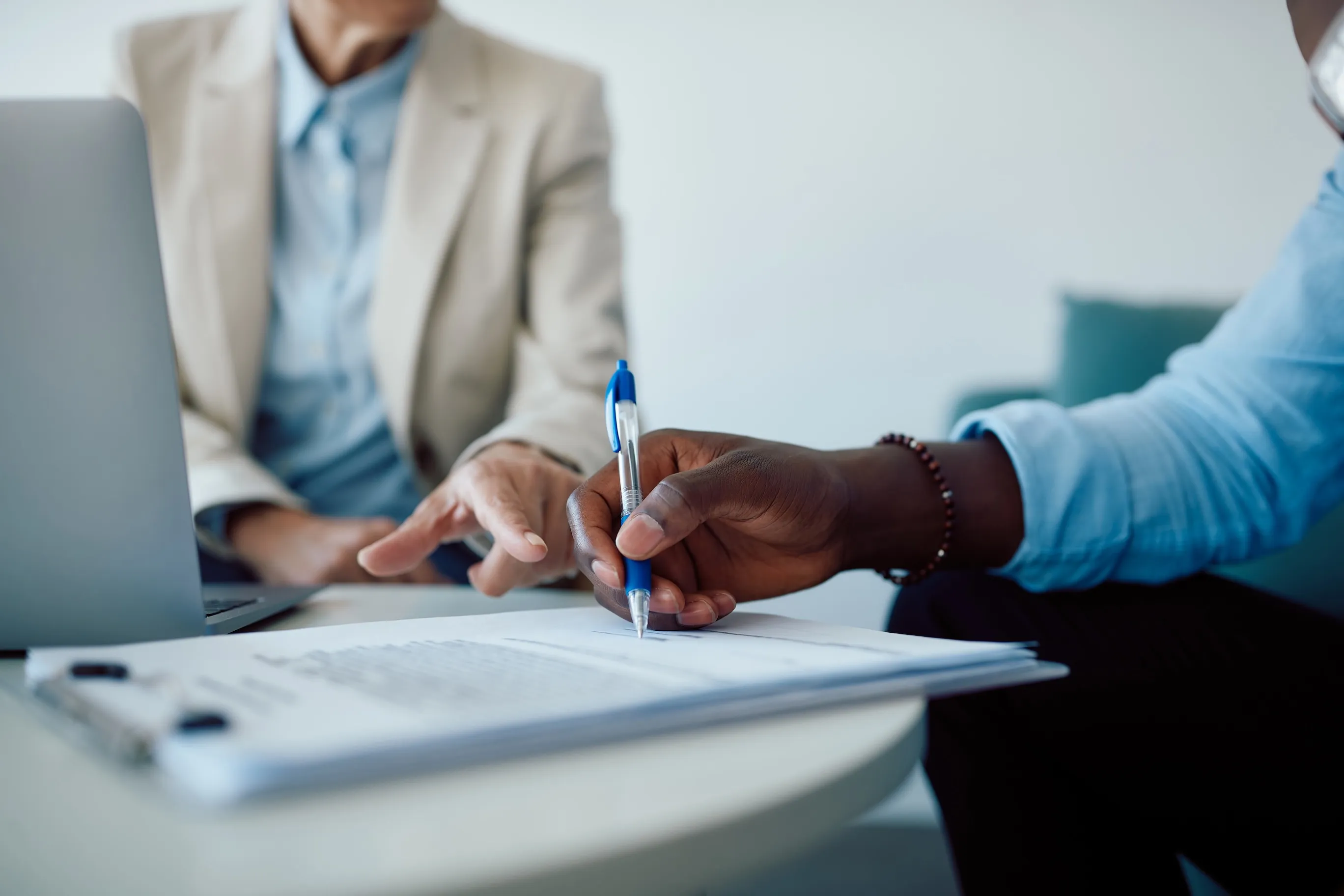 Close-up of black man signing contract with insurance agent in the office at Azusa Dental Clinic.