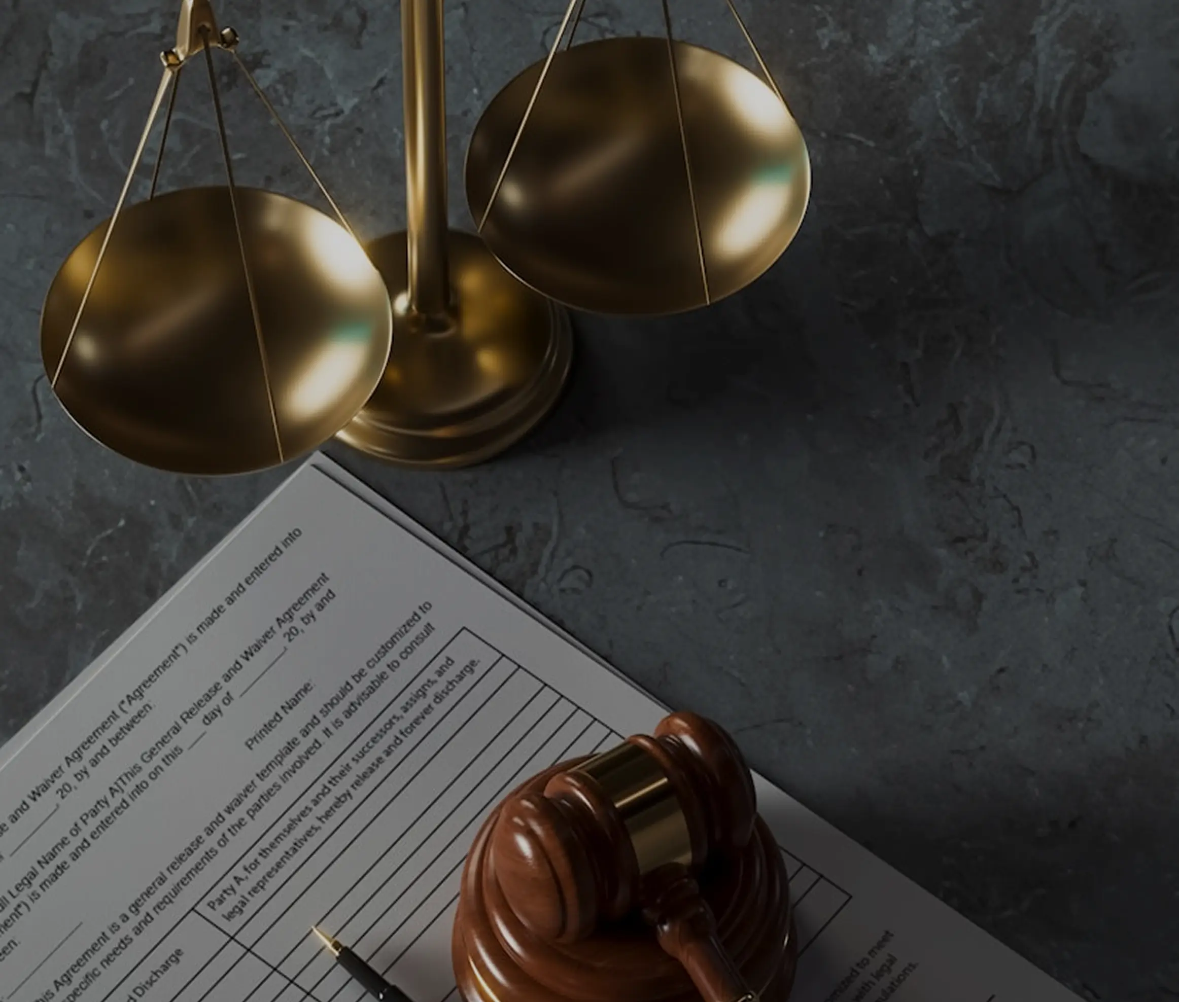 Golden balancing scales, a wooden gavel, and a legal document on a dark marble surface.