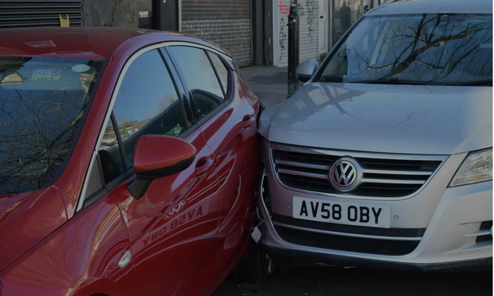Red car and silver Volkswagen car involved in a side collision on a street.