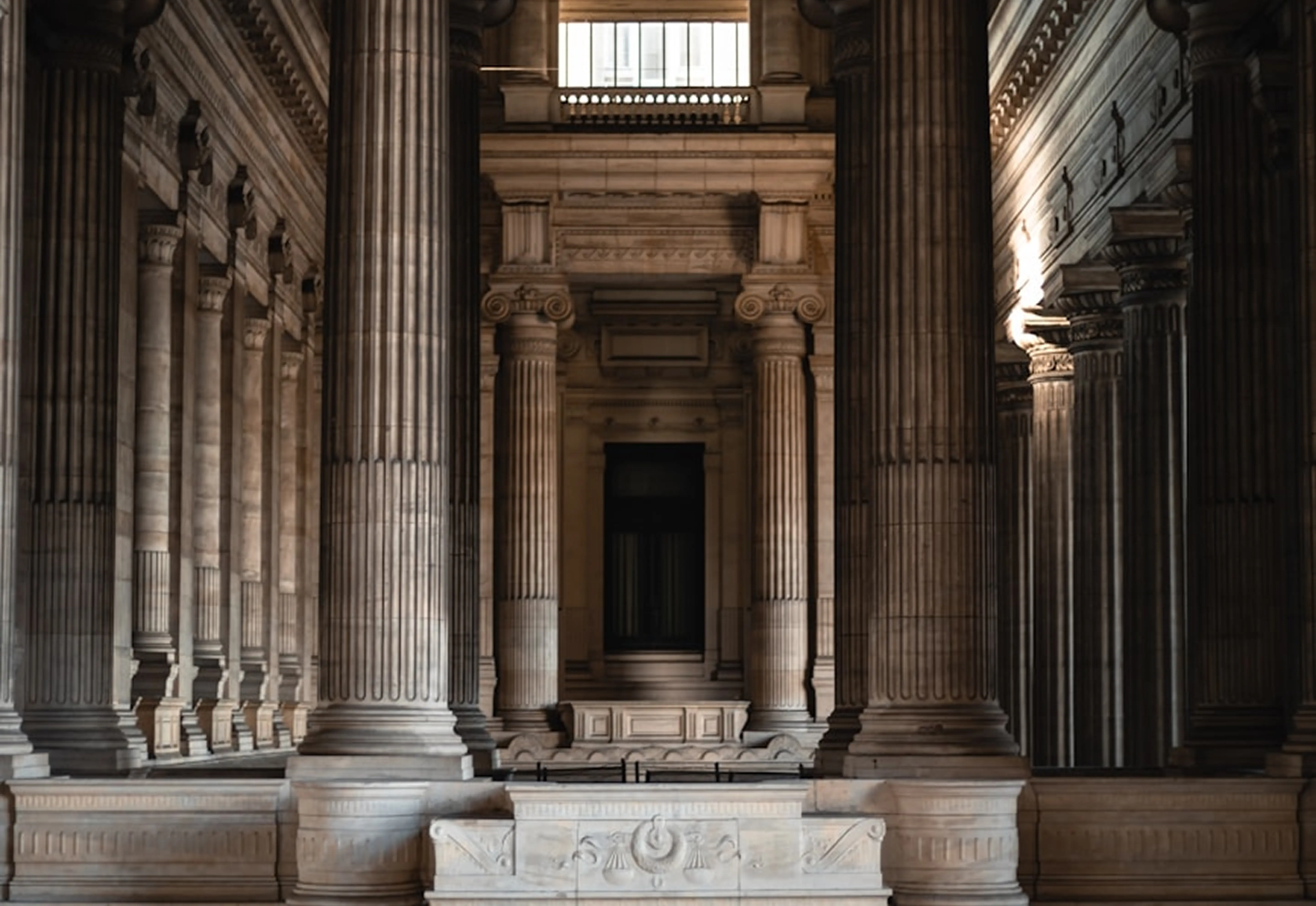 Interior view of a grand neoclassical building with large fluted columns and intricate architectural details.