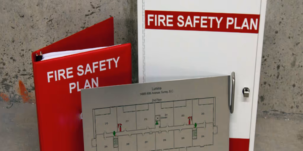 Red and white fire safety plan binders with a building floor plan attached to white one on a gray wall.