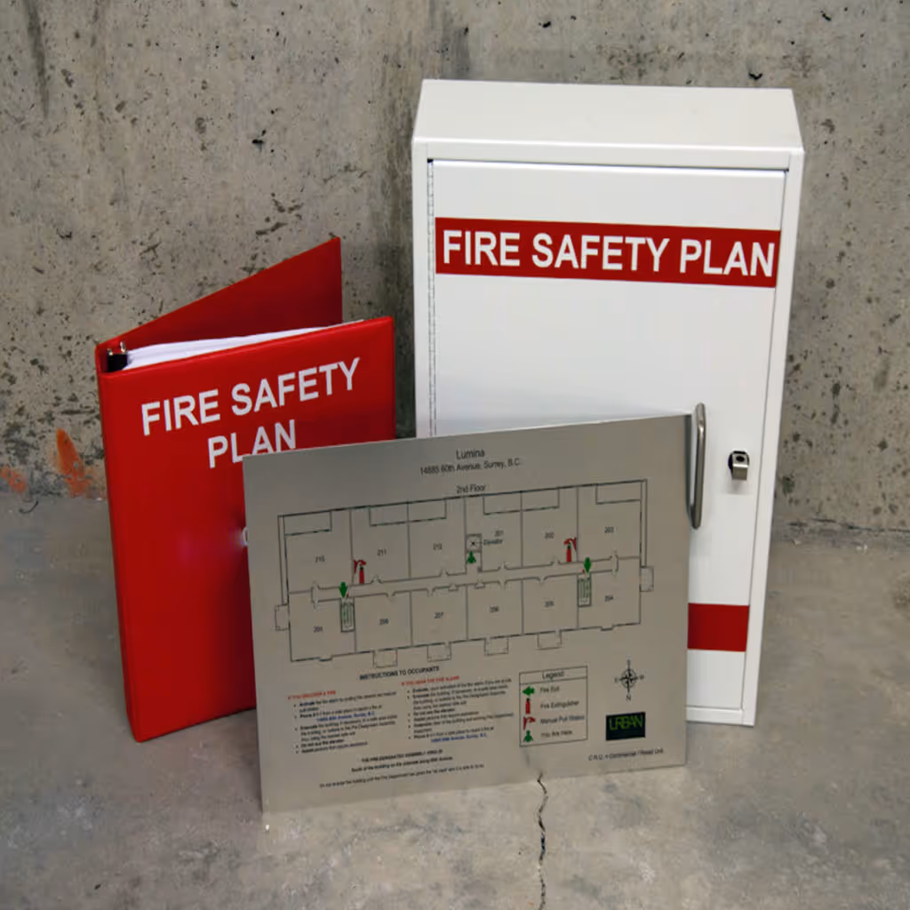 Fire safety plan folder, metal cabinet, and evacuation floor plan displayed on a concrete floor.