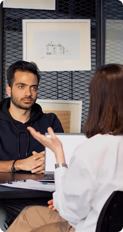 Man attentively listening to a woman talking during a meeting in a modern office.