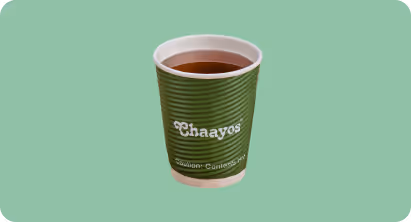 Green disposable cup filled with tea on a light green background, branded with 'Chaayos'.