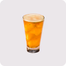 Glass of iced tea with foam on top against a plain background.