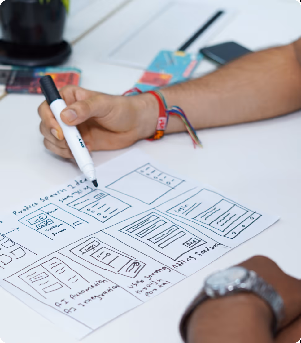 Person sketching a website wireframe layout on paper with a black marker pen.