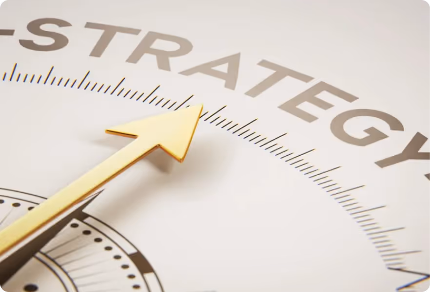 Close-up of a golden compass needle pointing toward the word 'STRATEGY' on a white background.