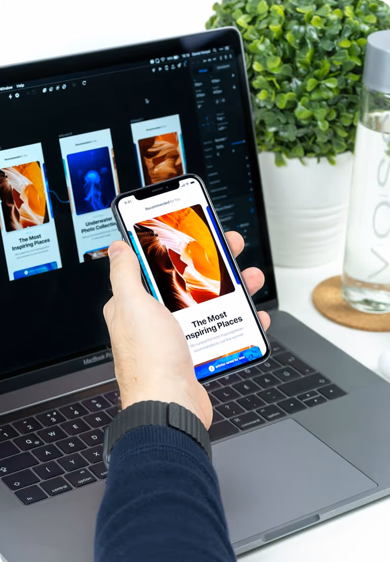 Person holding a smartphone displaying a photo app titled 'The Most Inspiring Places' in front of a laptop screen showing a similar design layout.
