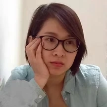 Woman with short dark hair and glasses resting her head on her hand with a thoughtful expression.