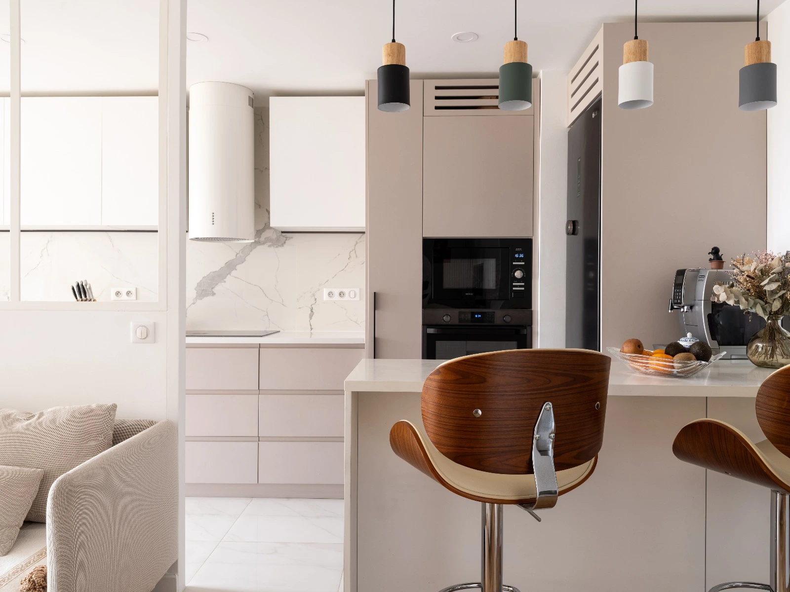 Modern kitchen with wood bar stools, marble backsplash, built-in microwave, and pendant lighting.