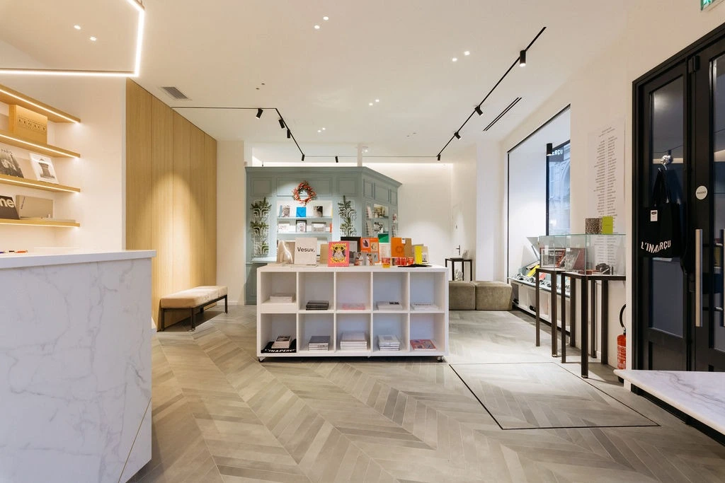 Modern shop interior with white shelves, books, displays, and a marble counter on light wood flooring.