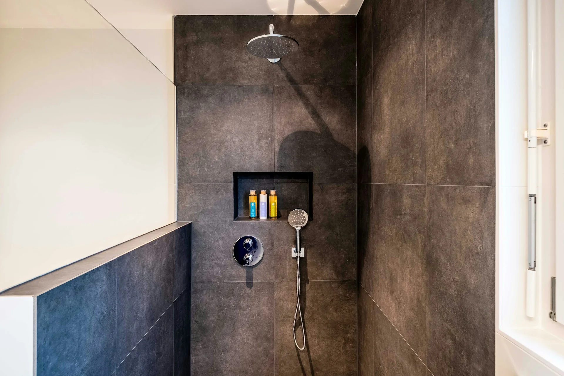 photo - a sleek walk in shower design with black tile
