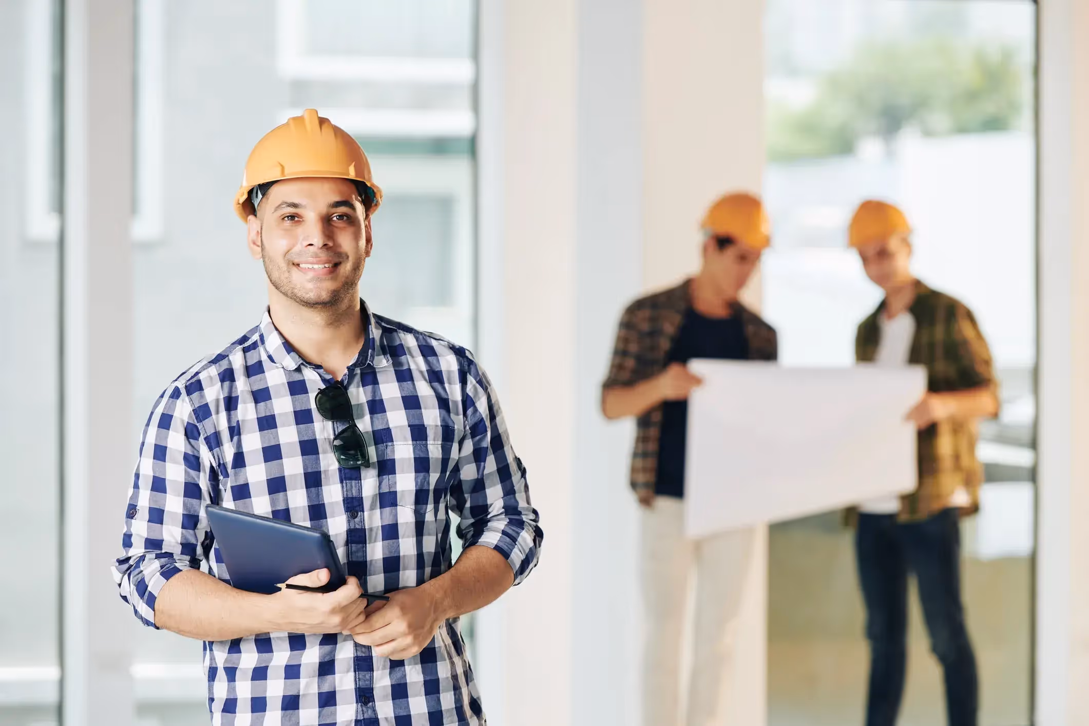Smiling construction manager holding a tablet on a building site.