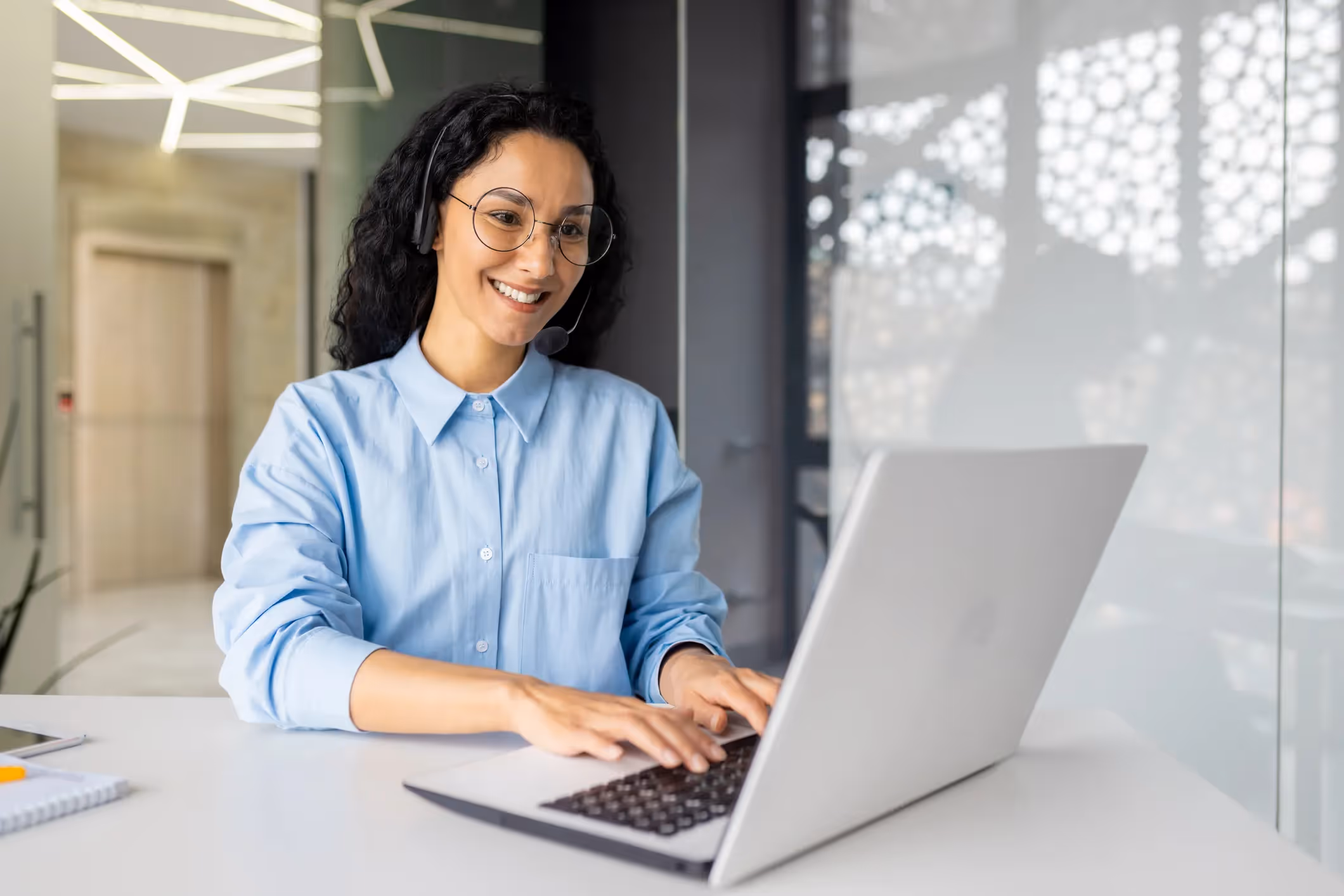 Happy woman in glasses and headset on a video call at her laptop.