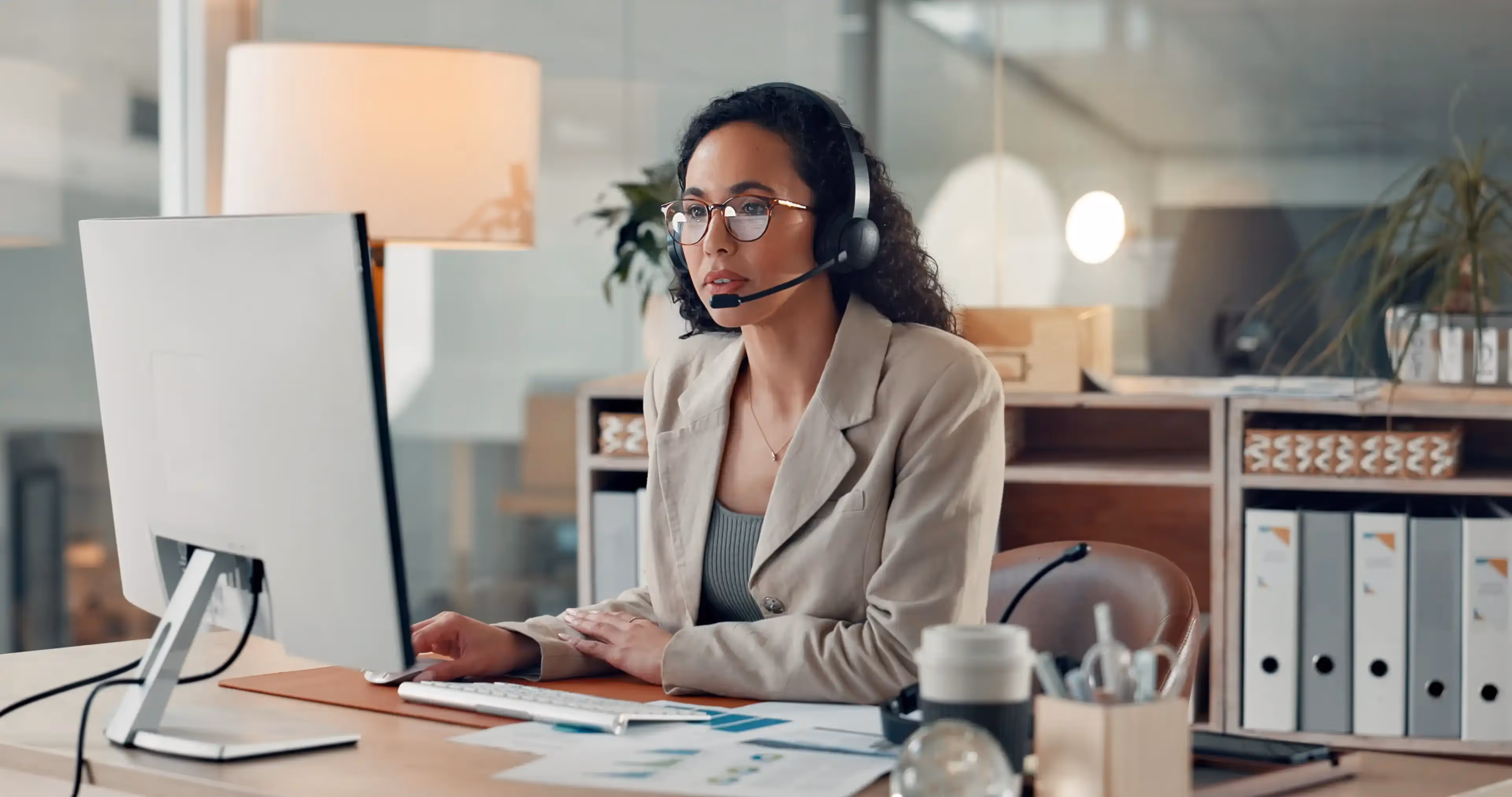 Smiling female agent in a headset and hoodie on a video call on her laptop.