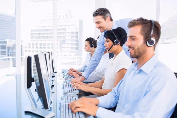 Call center team members wearing headsets and working on computers, illustrating professional appointment answering services for enhanced business efficiency.