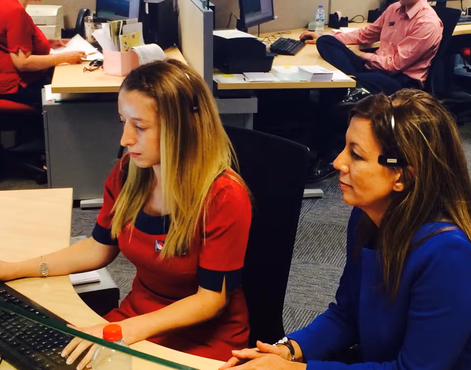 Customer service representatives in an office setting, engaged in call answering and information processing, showcasing teamwork and professionalism.