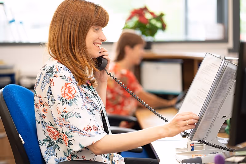 Woman on phone providing customer service in office, highlighting professional answering services for businesses in Houston.