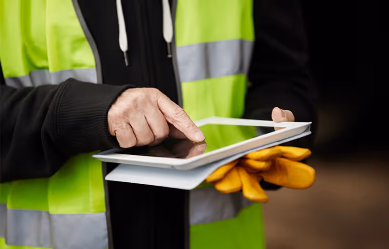 Person in a high-visibility vest using a tablet, representing virtual assistant technology for business productivity.