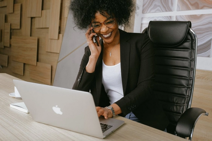 Smiling woman on call using laptop.