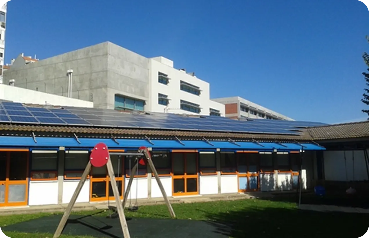 Rural building with solar panels on roof, various equipment outside, under a partly cloudy sky.