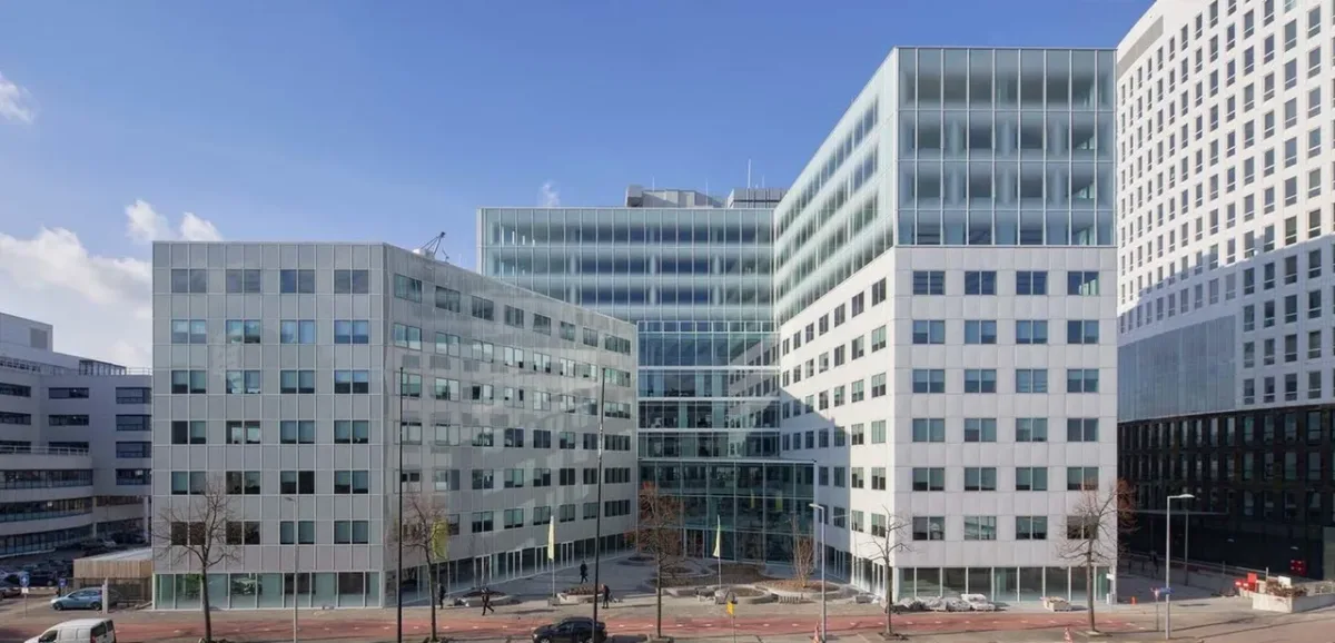 Modern kantoorgebouwen met glazen gevels onder een blauwe lucht in een stedelijk gebied.