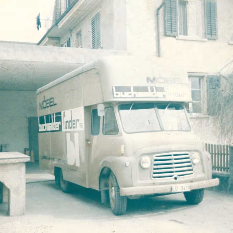 Altes Lieferwagenfahrzeug mit der Aufschrift Möbel Buchmüller Linder vor einem Gebäude.
