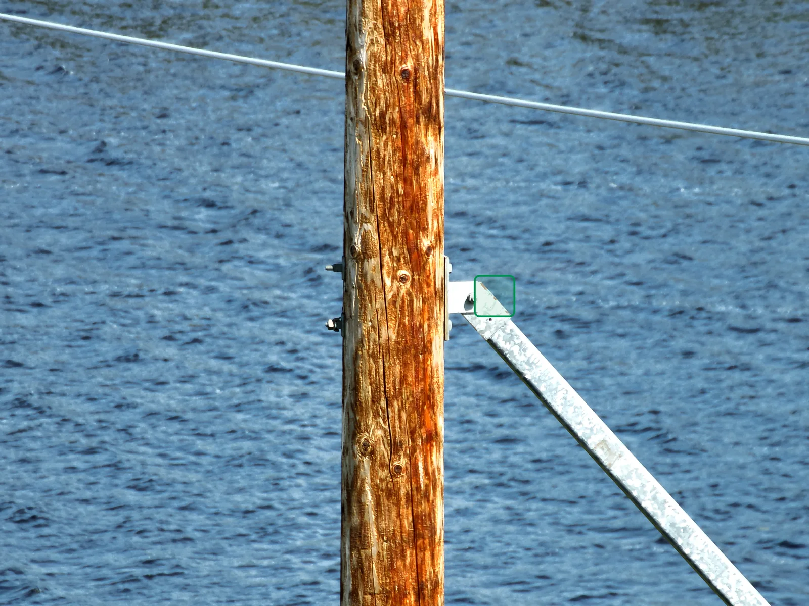 Utility pole and conductor hardware inspected by drone beside open water