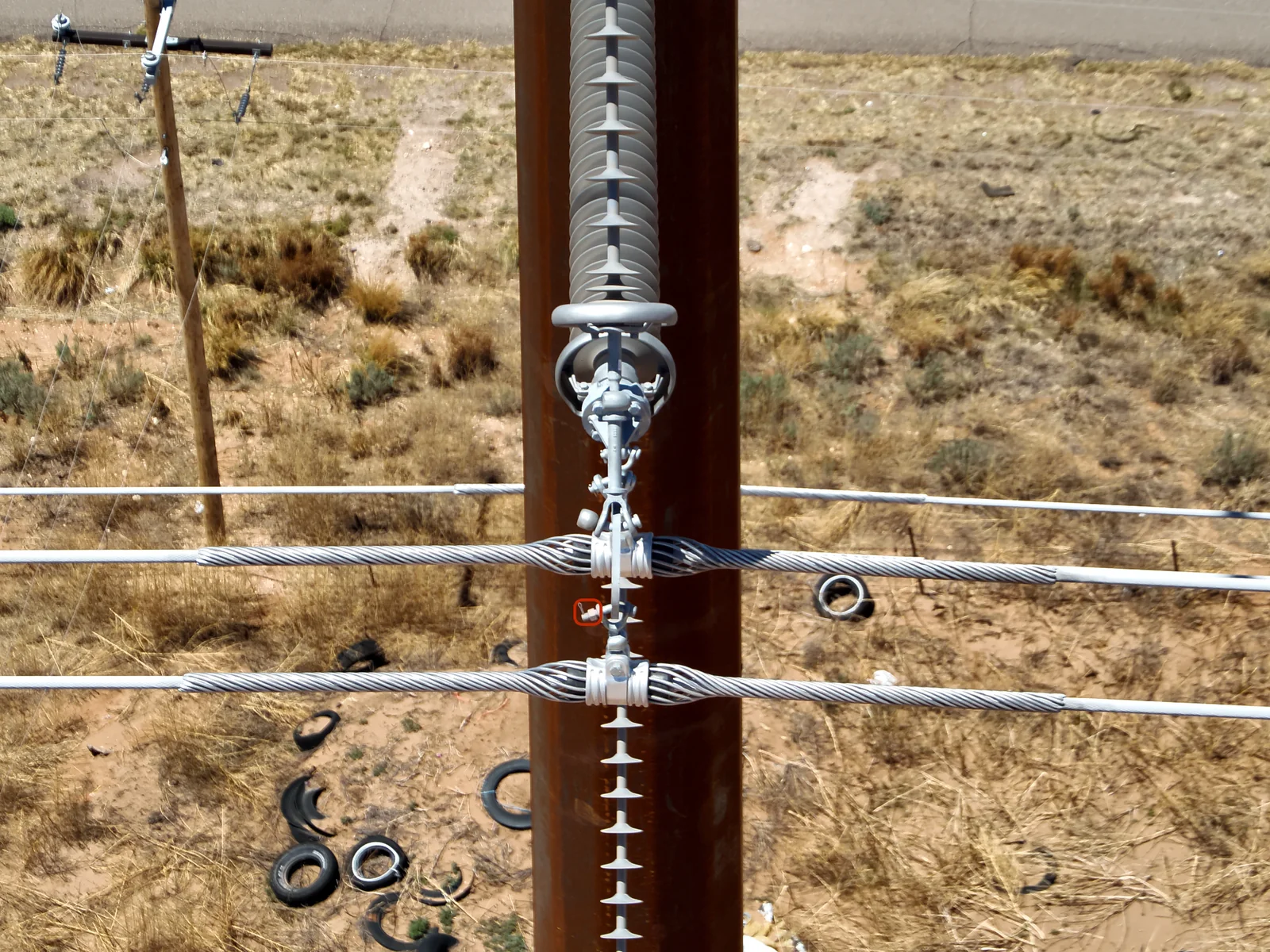 Drone inspection photo of distribution pole hardware with fallen components on the ground