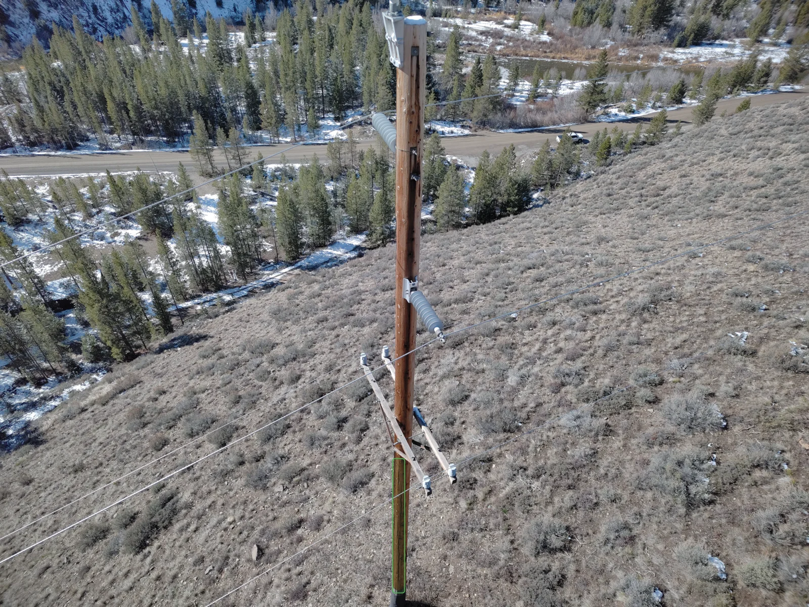 Drone view of a distribution line spanning a hillside during an aerial inspection campaign