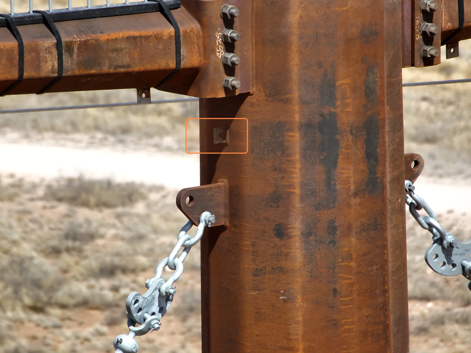 Drone close-up of flagged hardware on a newly built weathering-steel transmission pole during construction QA review