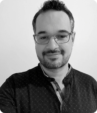 Portrait en noir et blanc d'un homme souriant avec des lunettes et une chemise à col mandarin.