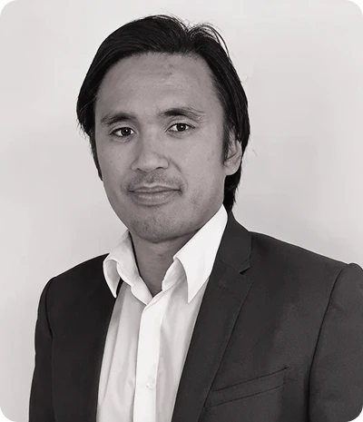 Portrait en buste d'un homme portant un costume sombre et une chemise blanche, posant devant un fond clair.