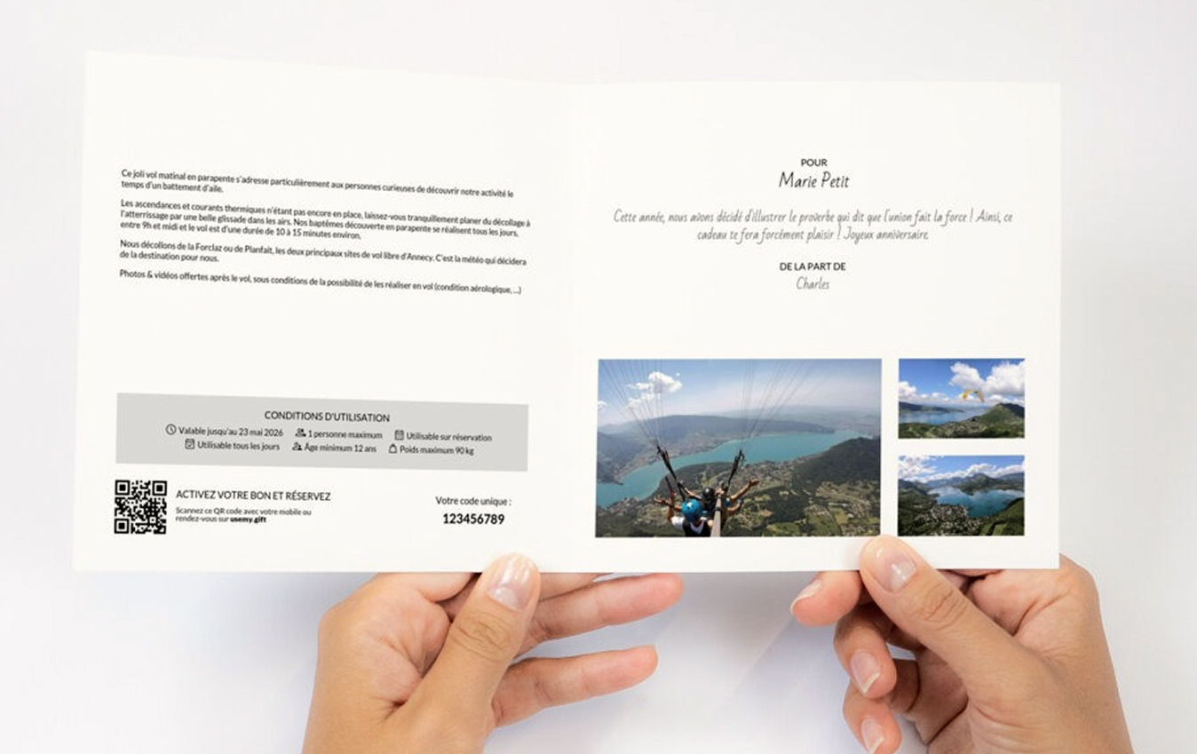 Personne tenant un bon cadeau de parapente avec texte, photos de vol au-dessus d’un lac et QR code.