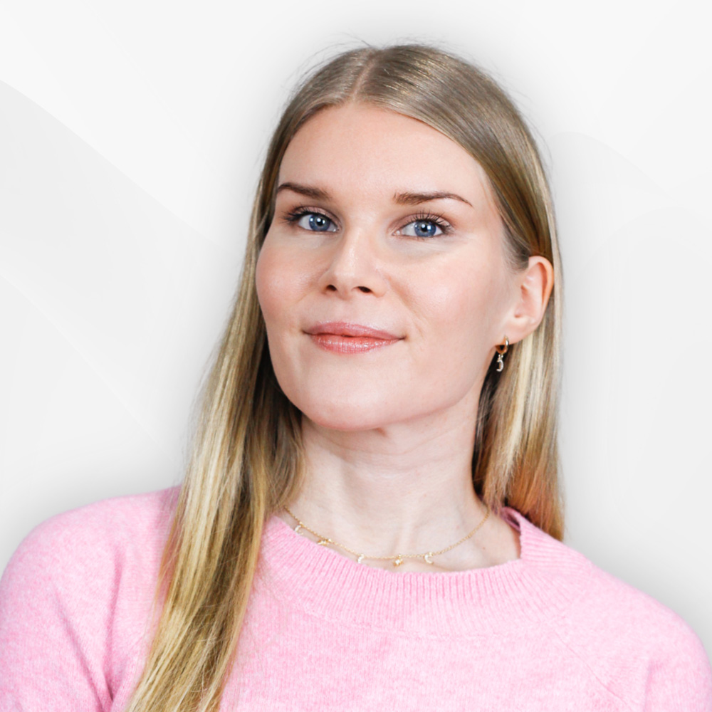 Smiling woman with long blonde hair wearing a pink sweater and gold necklace.