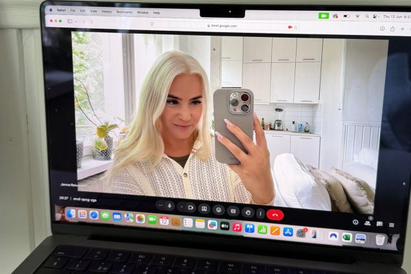 Woman with long blonde hair wearing a white sweater, smiling on a laptop video call.
