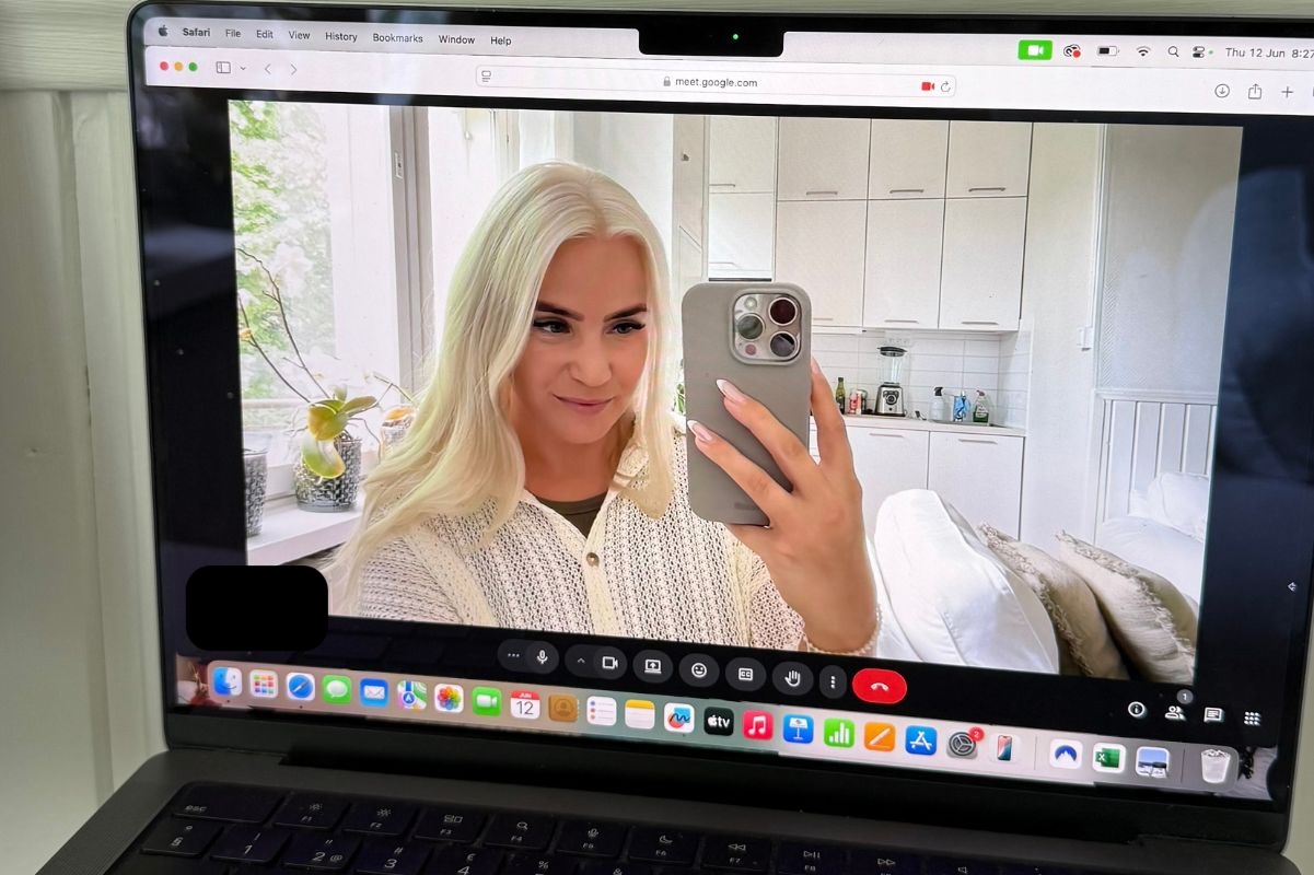 Woman with long blonde hair wearing a cream sweater takes a selfie during a Google Meet video call.
