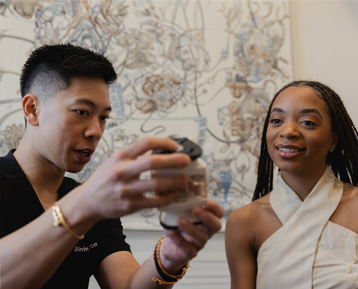 Man in black shirt holding a dental model next to a smiling woman in beige top.